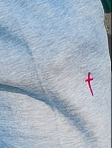 Close-up of a white towel with a red cross embroidery on a textured surface.